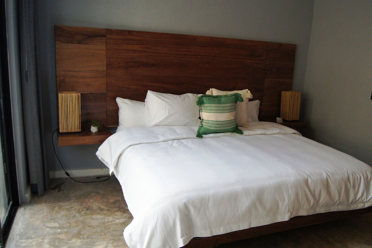 A hotel room with a large bed, a wooden headboard, and two bedside lamps.