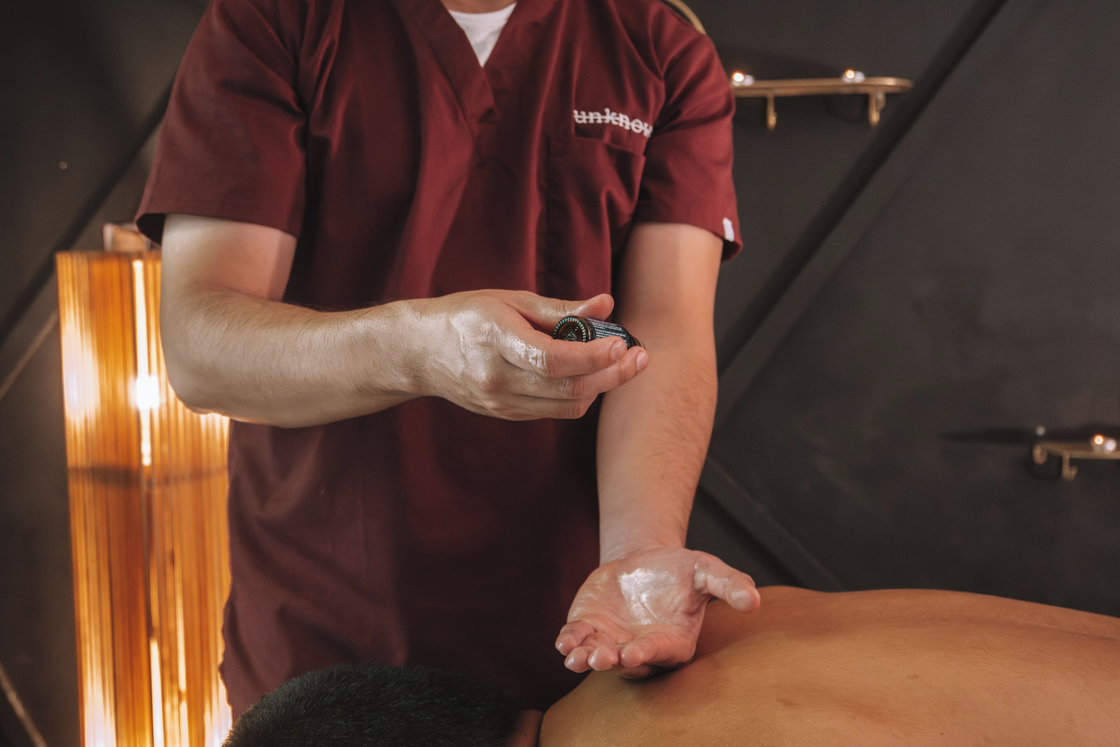 A person in a red shirt applying a product to another person's back.