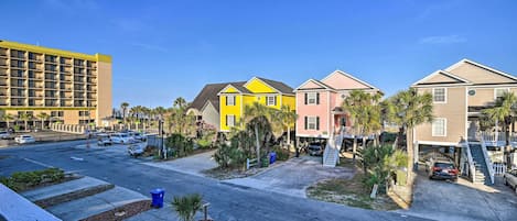 A residential street with colorful houses, a parking lot, and a hotel building.