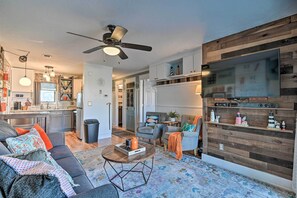 A modern living room with a sofa, coffee table, and a TV mounted on a wooden wall.