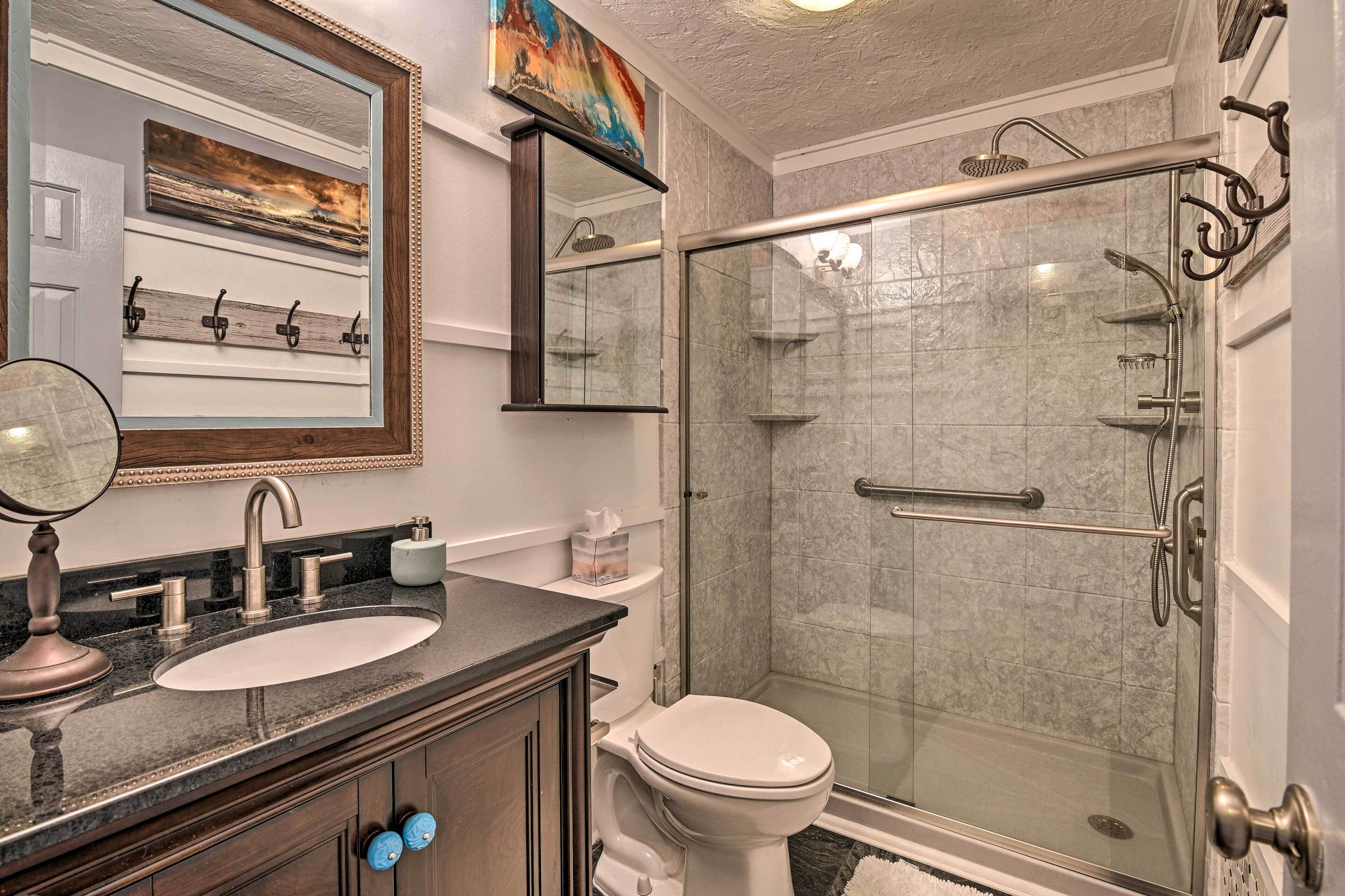 A bathroom with a sink, toilet, and glass-enclosed shower with a handheld showerhead.