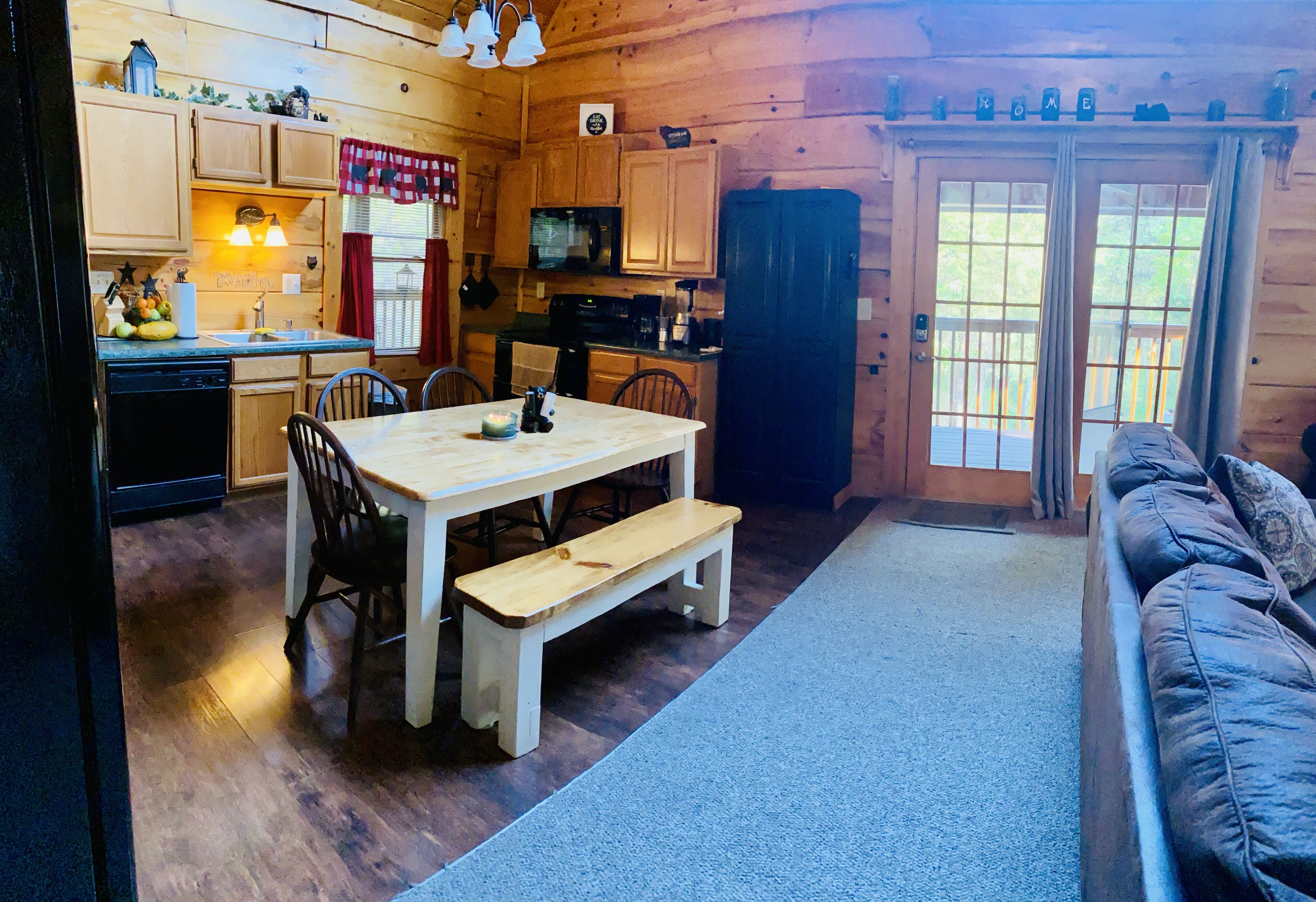 Une cuisine chaleureuse, aménagée dans le style d’un chalet, avec des meubles de rangement en bois, une table à manger avec des chaises, un banc et un canapé.