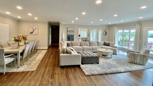 A spacious living room with a dining area, a sectional sofa, and a coffee table. - Massive Lakehouse - Infinity Pool, Hot Tubs, Dock, Firepit (Gainesville)