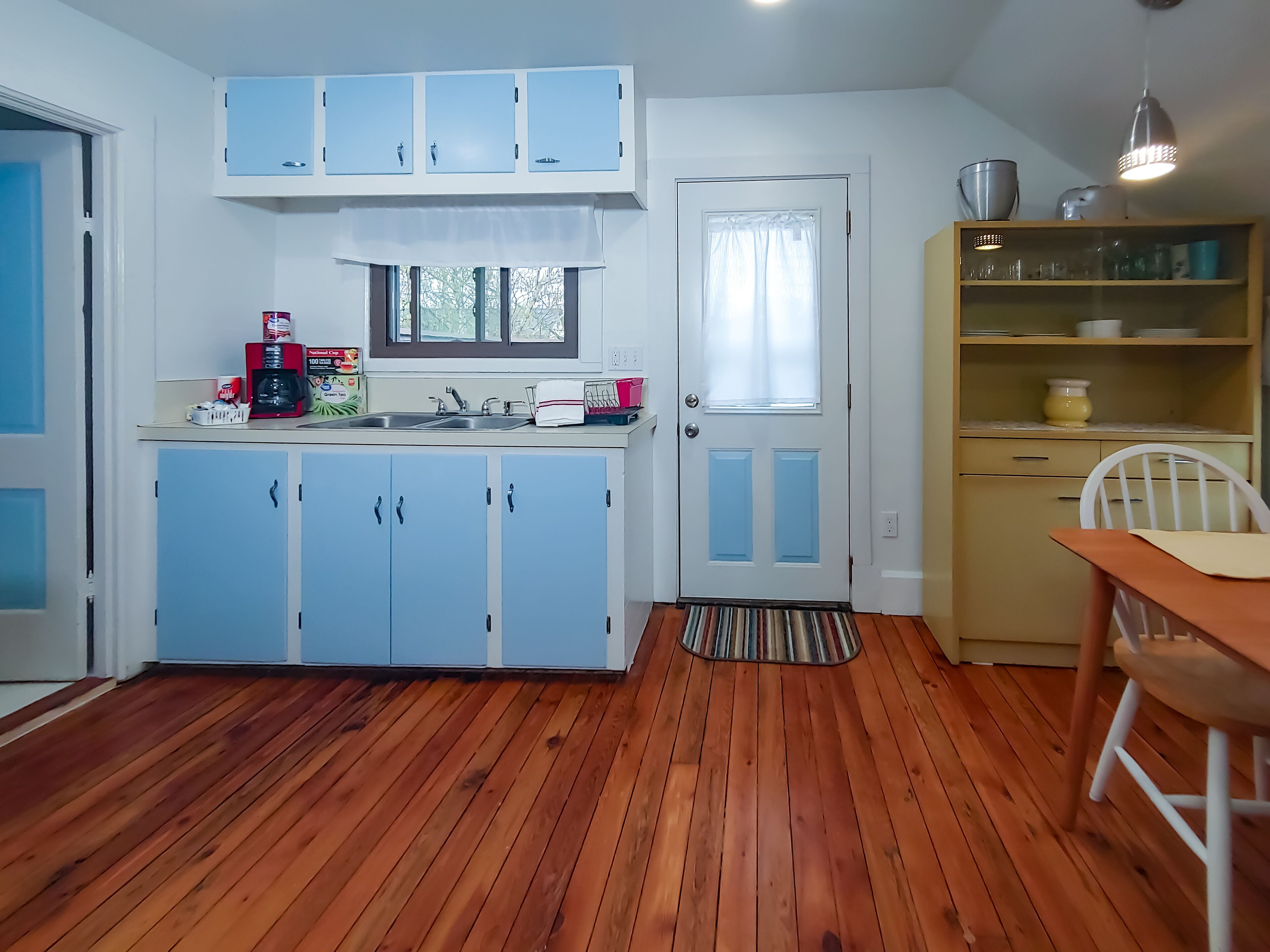 A compact kitchen with blue cabinets, a sink, and a window.