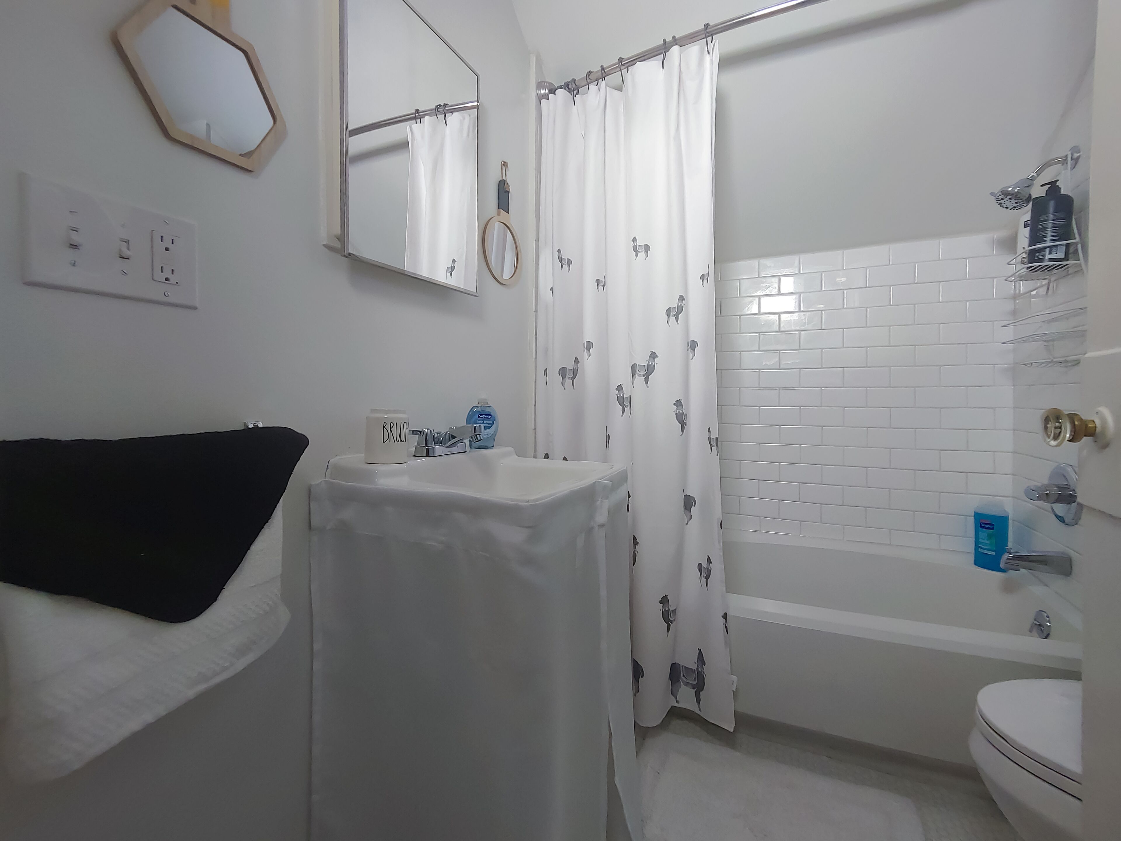 Un baño con un lavabo blanco, un espejo, una cortina de ducha y una bañera.