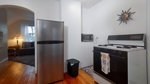 A compact kitchen with a stainless steel refrigerator, a microwave, and a gas stove. - Downtown home blocks to the beach w/ king bed, deck fire pit & air conditioning (Manistee)