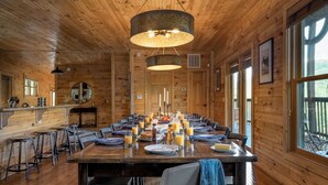 Une cabane en bois avec une grande table à manger dressée pour le petit-déjeuner, avec du jus d’orange et des viennoiseries.