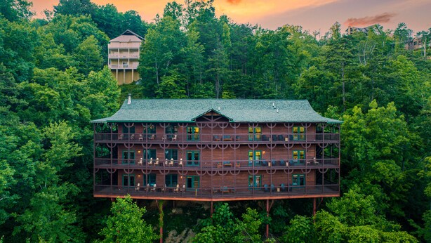 Un immeuble en bois à plusieurs étages, doté de balcons et entouré d’une forêt dense.