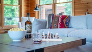 Un intérieur en bois avec une table sur laquelle se trouvent une bouteille de Jameson Cold Brew, un bol de pop-corn, un verre contenant des objets rouges et un jeu d’échecs.