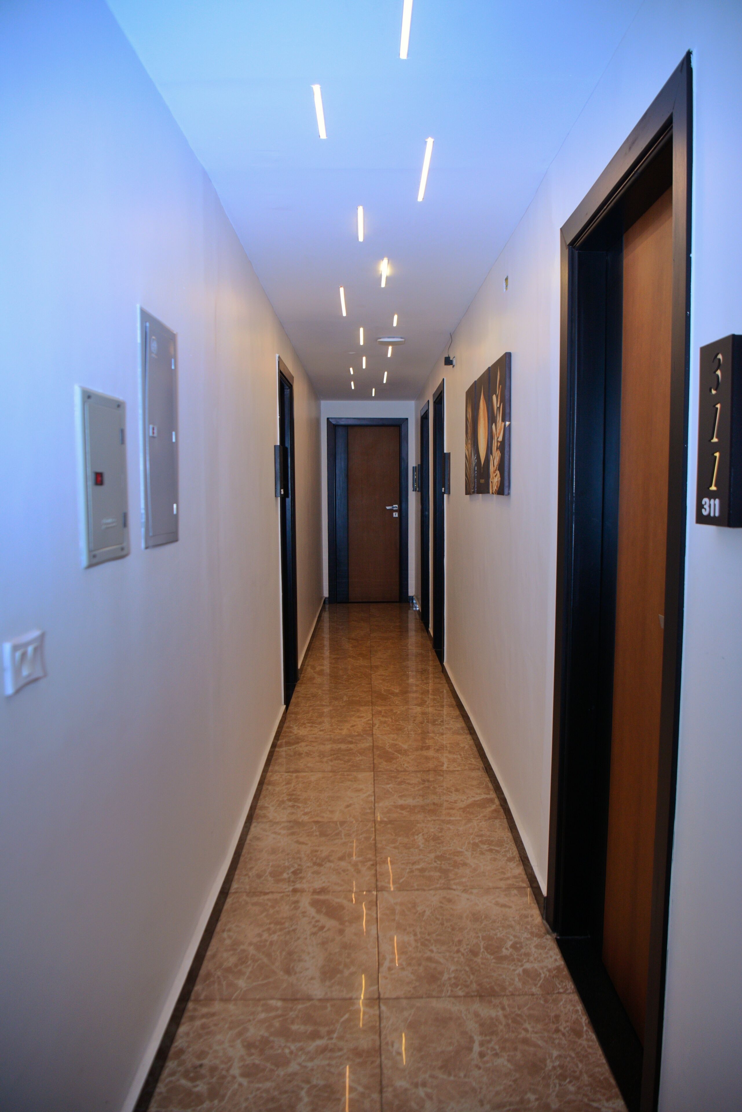 Un corridoio con pavimento in marmo, illuminazione a incasso e porte numerate.