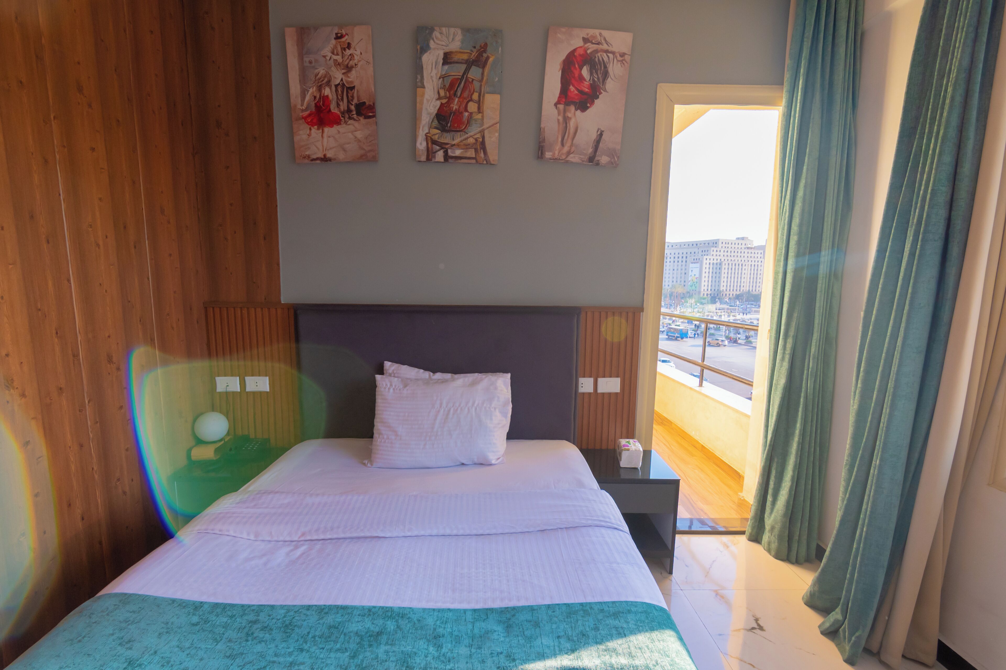 Une chambre d’hôtel avec un lit, une table de chevet et une vue sur la ville par la fenêtre.