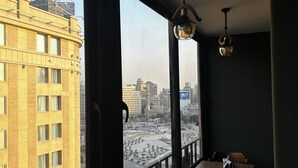 Una habitación con ventanas amplias, un balcón y una mesa con sillas.