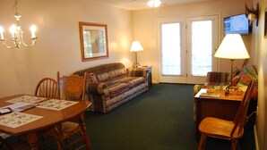 Un salon comprenant un canapé, une table à manger avec des chaises, une lampe, un téléviseur et un ventilateur de plafond.