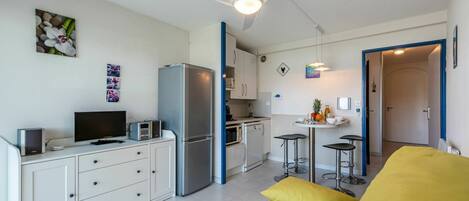 A compact living space with a kitchenette, a dining area, and a sofa with yellow cushions.