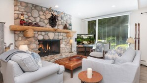 Una sala de estar con chimenea de piedra, un sofá, una mesa de centro y un televisor.