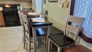 Een keuken met een fornuis, oven en een eettafel met stoelen.