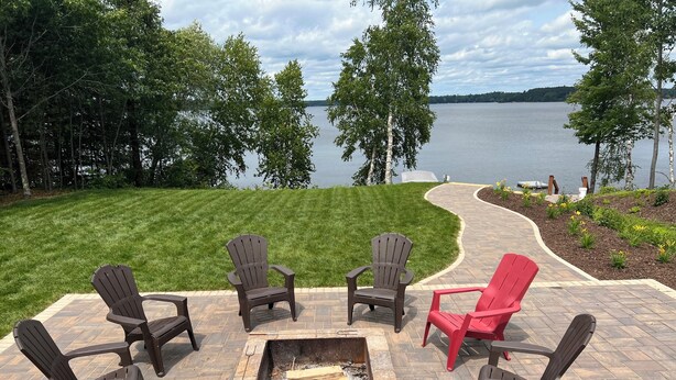 An outdoor seating area with Adirondack chairs and a fire pit, overlooking a lake. - Beautiful 6 bedroom 3 bath lake front home with view of Lake Nokomis! (Tomahawk)