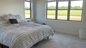 Een slaapkamer met een bed, twee ramen, een plafondventilator en een vloerbedekking.