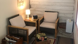 Een knus vertrek met rieten meubels, een tafeltje met een lamp, een decoratief bord en een radiator.