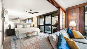 Une chambre d’hôtel avec un lit, un canapé, un bureau, une lampe et une fenêtre avec des stores.