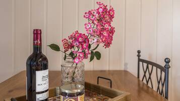 En flaska vin, ett glas med sylt och rosa blommor på ett träbord.