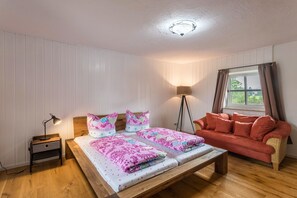 A room with a bed, bedside table, lamp, and a window with curtains.