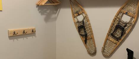 A corner of a room with a wooden bench, a wall-mounted rack, and a pair of skis.