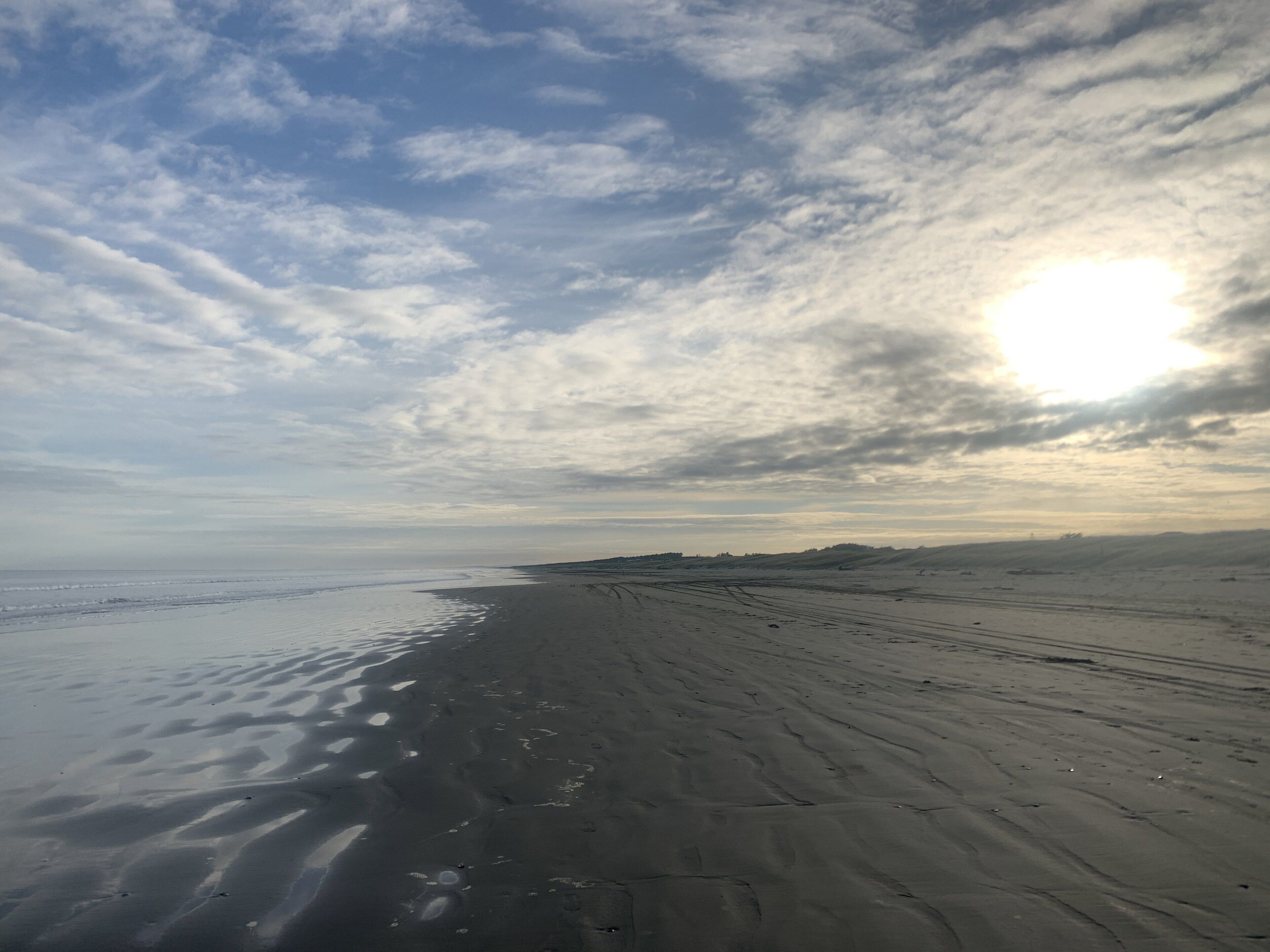 Ein Strand mit einer weiten Sandfl äche und einer deutlich erkennbaren Küstenlinie.