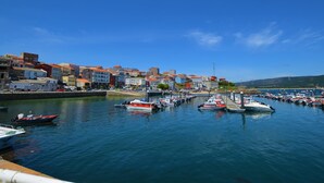 Un port de plaisance avec des bateaux amarrés, un ciel bleu dégagé et des bâtiments le long de la promenade.