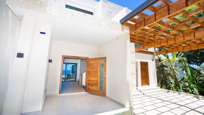 Una casa moderna con una pergola in legno, un patio piastrellato e vista sull'interno.
