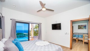 Una camera da letto con un letto, una ventola a soffitto, una TV e vista sull'esterno.