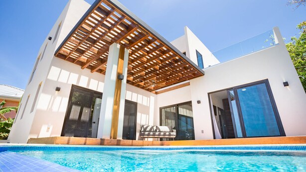 Una casa moderna con piscina, ampie finestre e una pergola in legno.