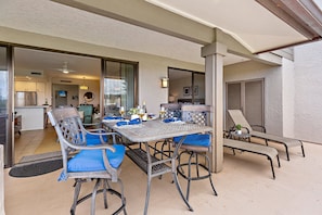 An outdoor patio with a table set for dining, surrounded by chairs and a lounge area.