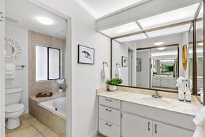 Une salle de bain moderne équipée d’une baignoire, de toilettes et d’un meuble-lavabo avec un grand miroir.