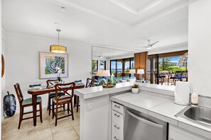 A modern kitchen with a dining area, large windows, and a view of the outdoors.