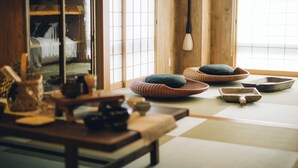 Una habitación tradicional japonesa con suelo de tatami, una mesa de madera baja y un fusuma que da a una cama.