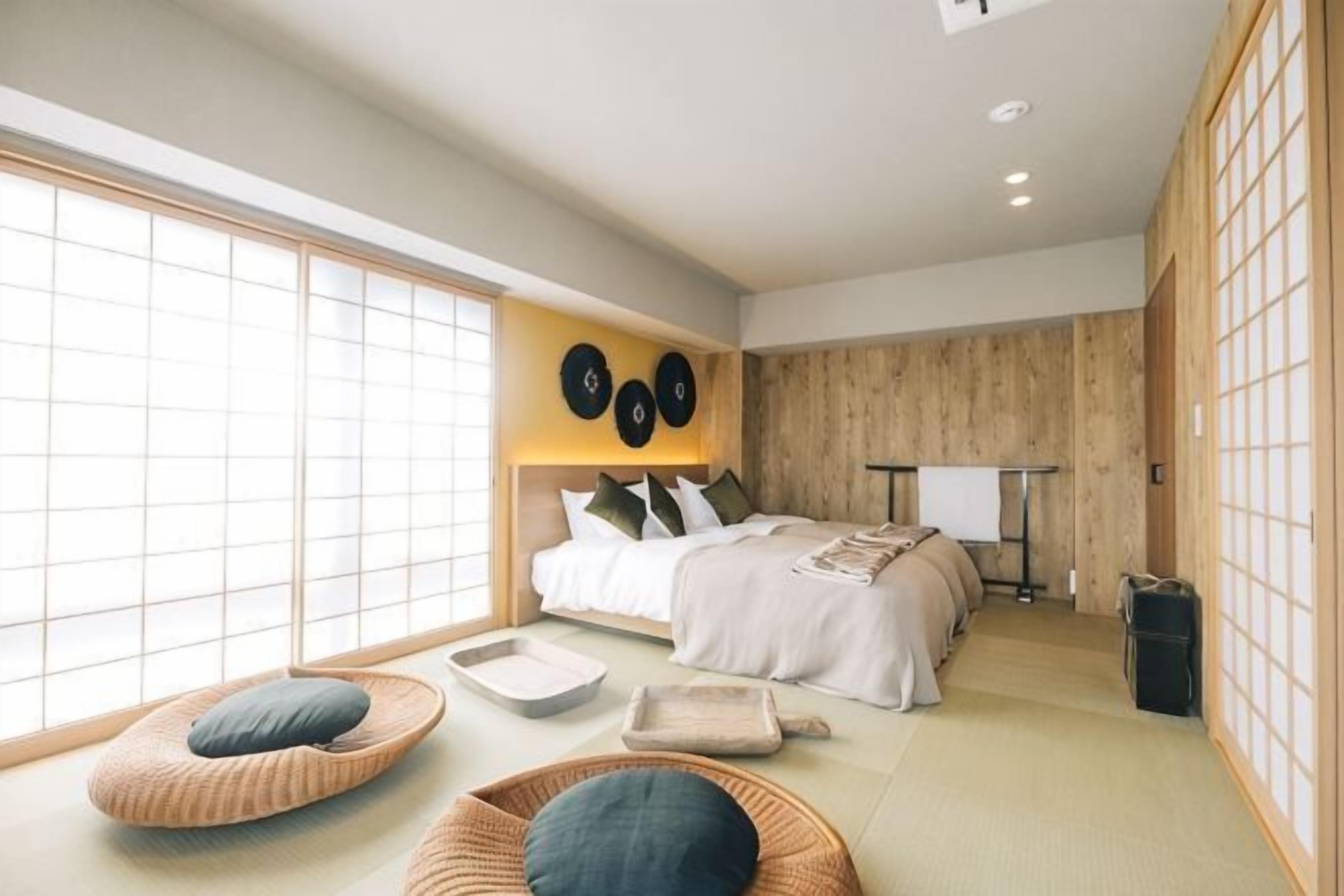 A modern bedroom with a large window, a bed with pillows, a bedside table, and a traditional Japanese sliding door.