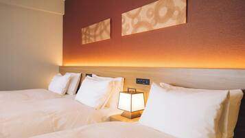 A hotel room with two beds, a nightstand with a lamp, and a wall-mounted control panel.