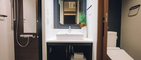 A modern bathroom with a shower, sink, and toilet.