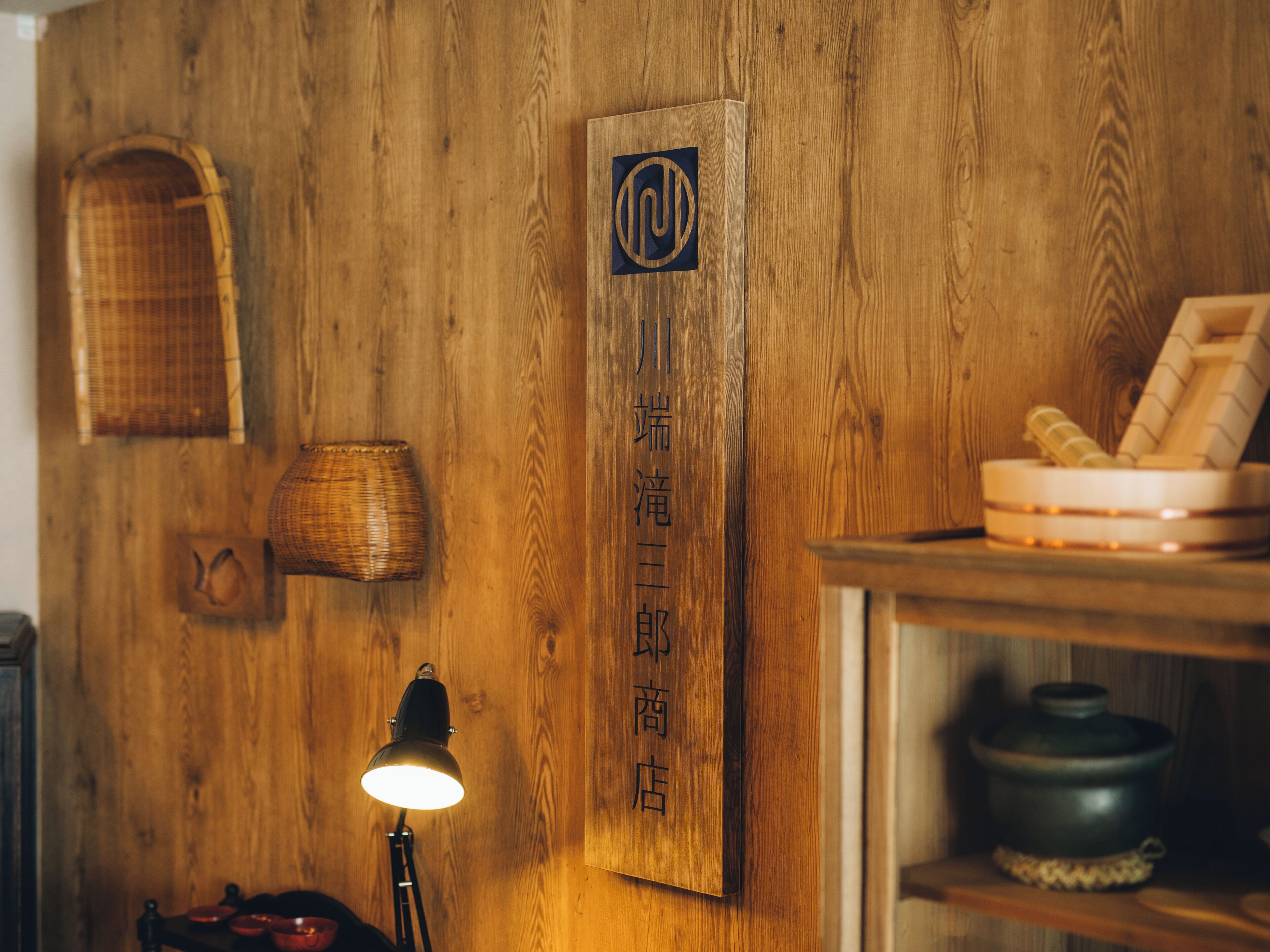A wooden wall with a sign, a lamp, and a shelf with items.