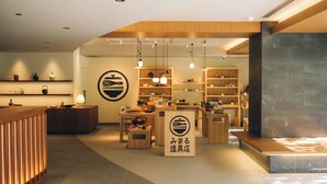 Un interior moderno con muebles de madera, estantes con utensilios de cocina y un letrero con caracteres japoneses.