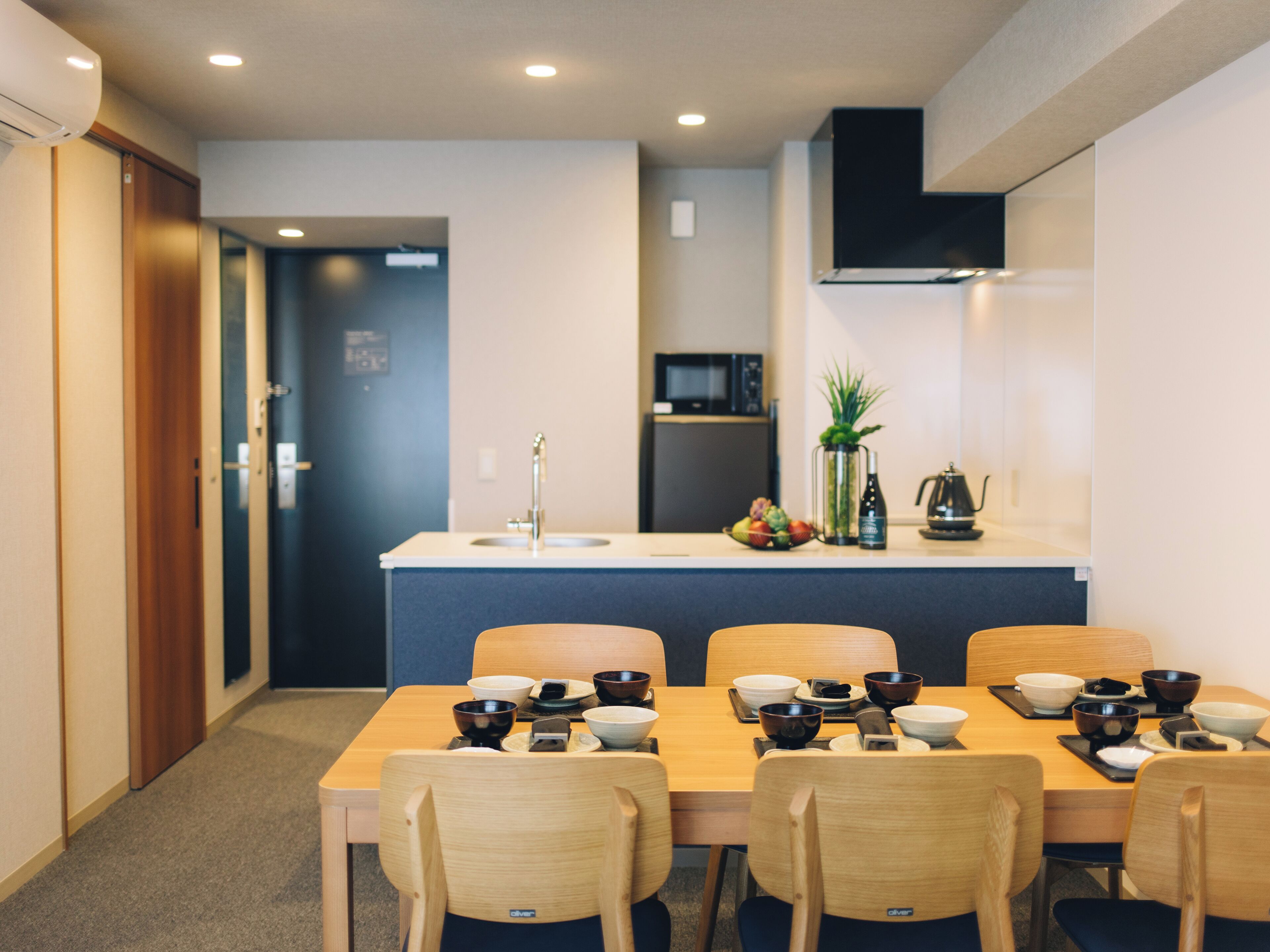 Una cocina moderna con una isla central, un comedor con sillas de madera y un microondas sobre la isla.