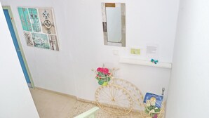 Ein Flur mit weißer Wand, einem Spiegel, einem Regal mit einer Karte und einem dekorativen Metallfahrrad mit Blumen.