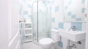 Ein modernes Badezimmer mit Duschabtrennung aus Glas, einer weißen Toilette und einem Waschbecken mit Spiegel.