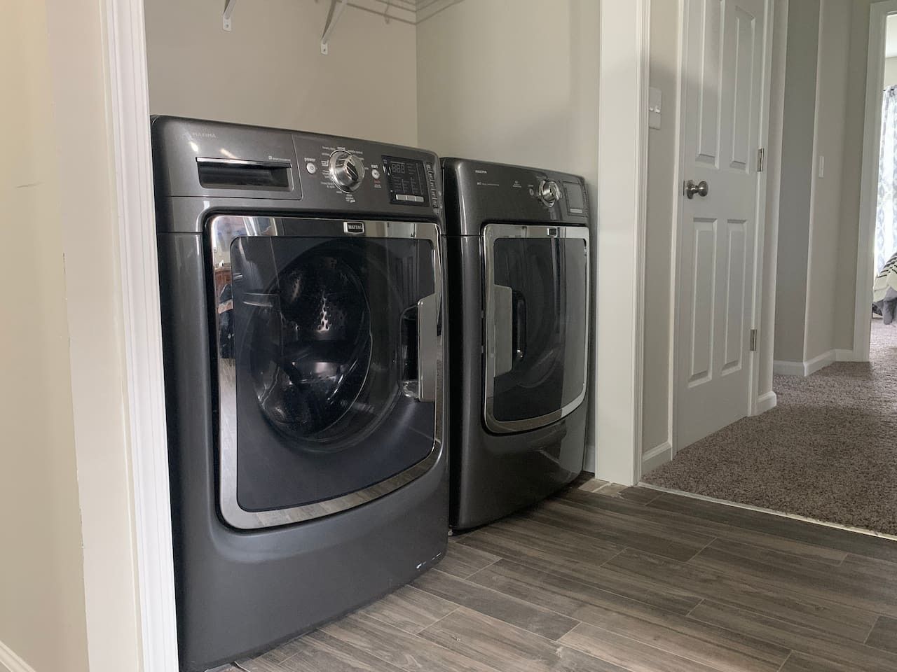 A laundry room with two front-loading washing machines and a door leading to another room.