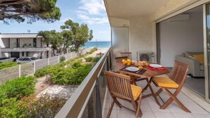 A balcony with a table set for two, overlooking a beach and a residential area. - De la Plage by Interhome (Cavalaire)