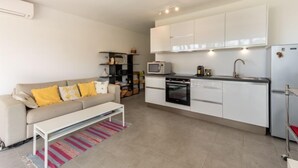 A compact living space with a kitchenette, a sofa with yellow cushions, a coffee table, and a striped rug. - De la Plage by Interhome (Cavalaire)