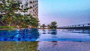 Una piscina con vistas a un edificio alto y una vía de tren al fondo.