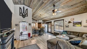 A spacious living area with a wooden ceiling, a dining area, and a kitchen with modern appliances. - Arn Barn Cabin (Lead)