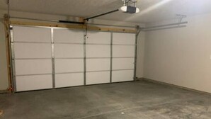 Un garaje con piso de concreto y puerta cerrada.